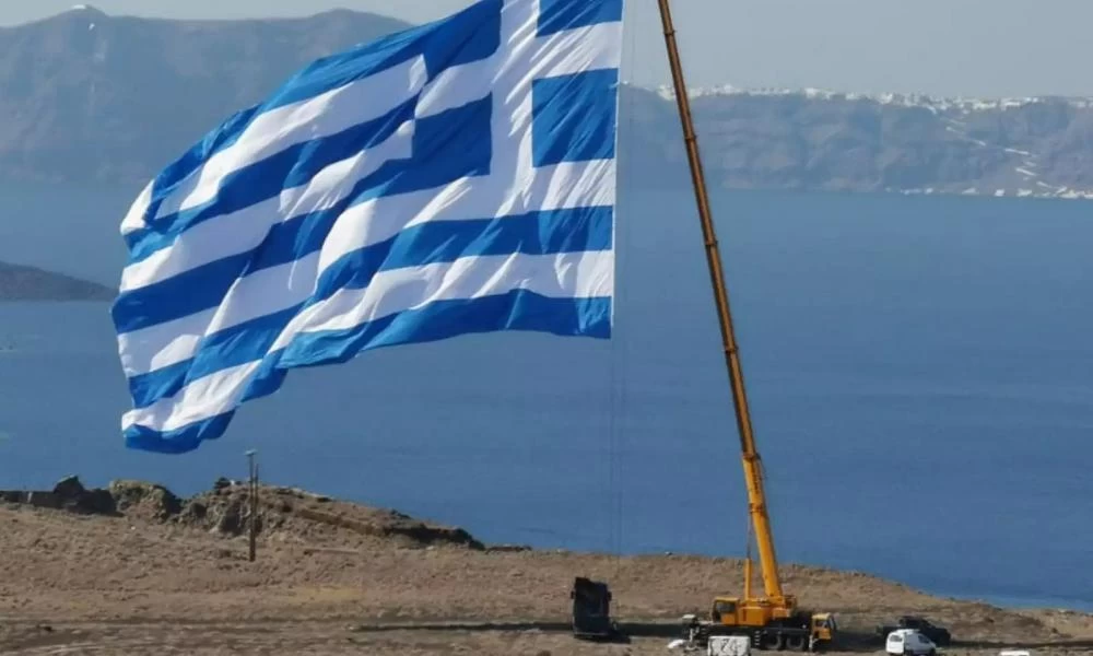 Σαντορίνη: Περήφανη κυματίζει η μεγαλύτερη ελληνική σημαία–Την ύψωσαν με γερανό (βίντεο-εικόνες)